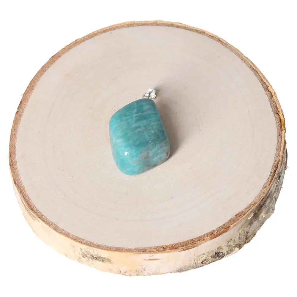 Amazonite AA Tumbled Pendant on wooden base showcasing vibrant blue-green hues and natural beauty.