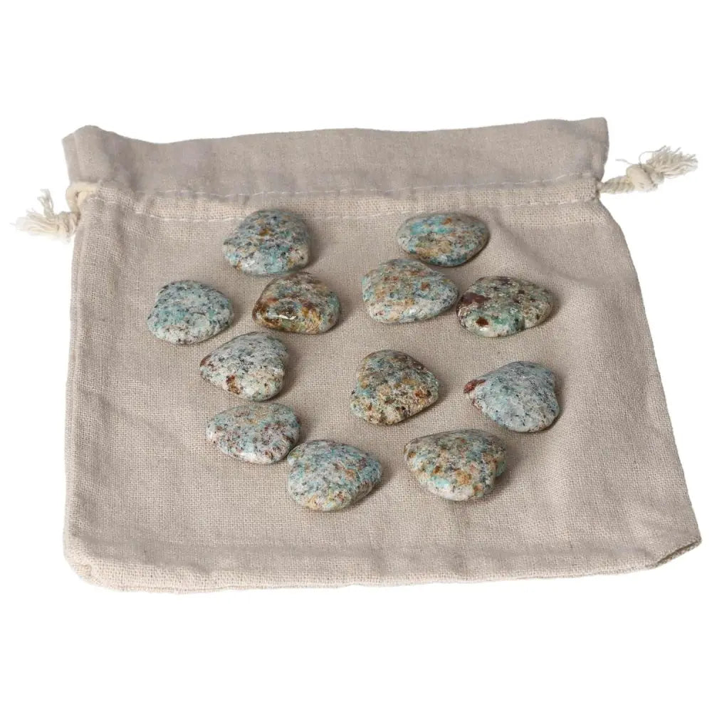 Collection of small Amazonite heart stones on a beige pouch, known for harmony and balancing emotions, offering a calming effect.