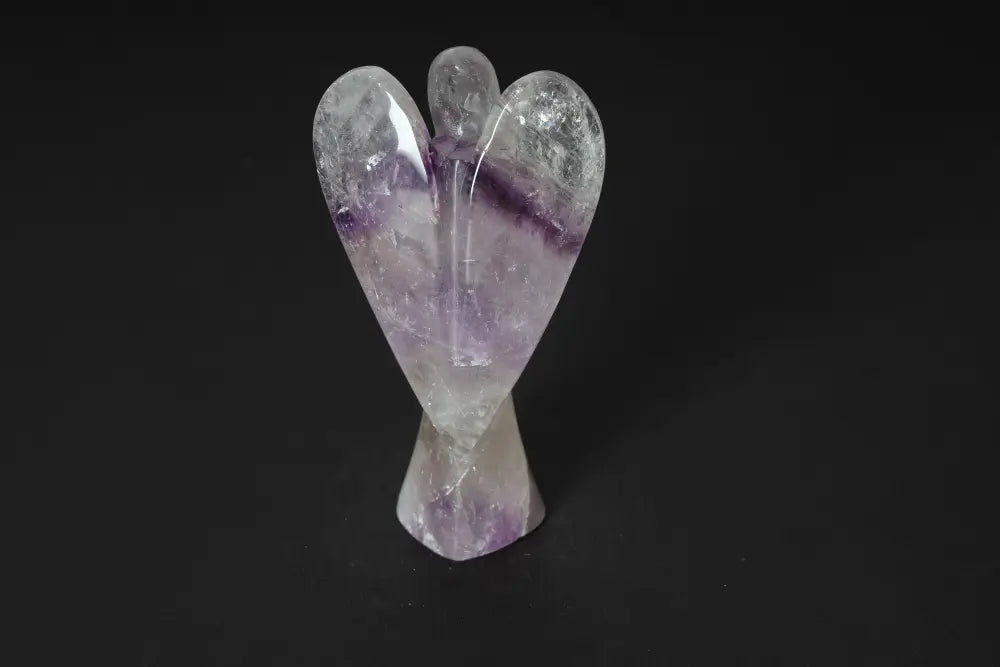Angel-shaped 13 cm amethyst crystal, known for reducing stress, boosting energy, and enhancing concentration, on a dark background.