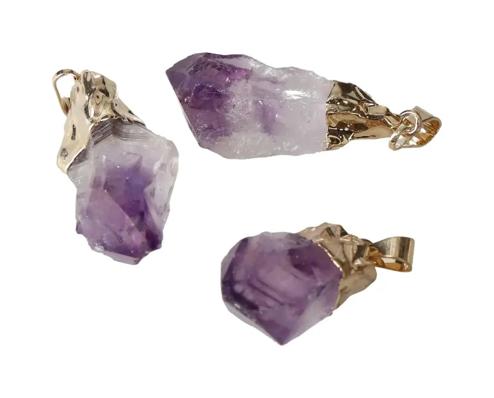 Three small amethyst point pendants with gold settings, showcasing their rich purple hues and crystalline textures.