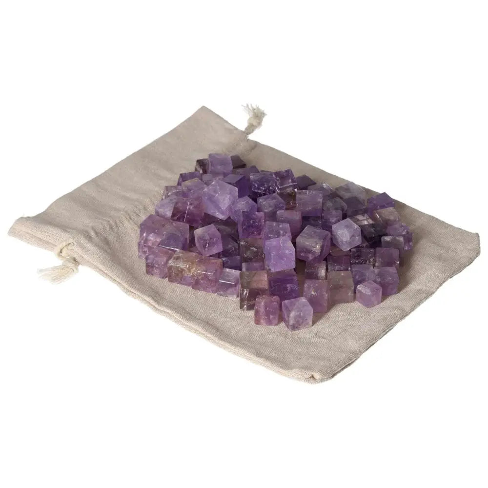 Amethyst small cubes on a beige cloth, known for reducing stress, boosting energy, enhancing concentration, and providing emotional stability.