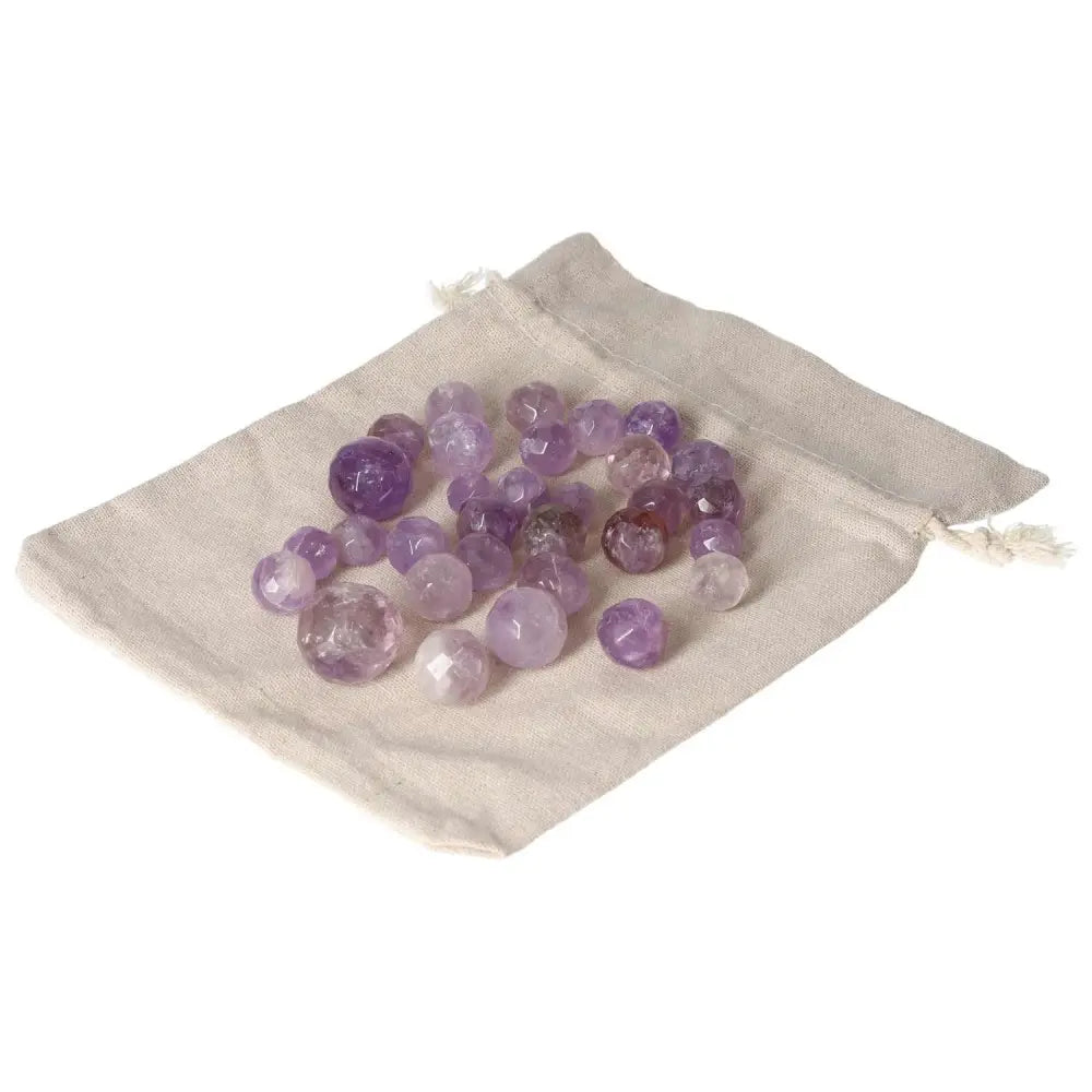 Collection of small geometric amethyst spheres displayed on a cloth, promoting relaxation, energy, and enhanced concentration.