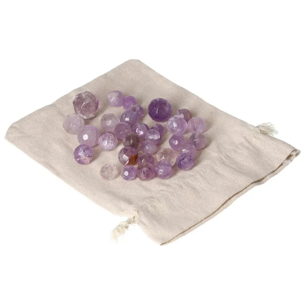 Amethyst small geometric spheres on a beige pouch, known for reducing stress, boosting energy, and enhancing concentration.
