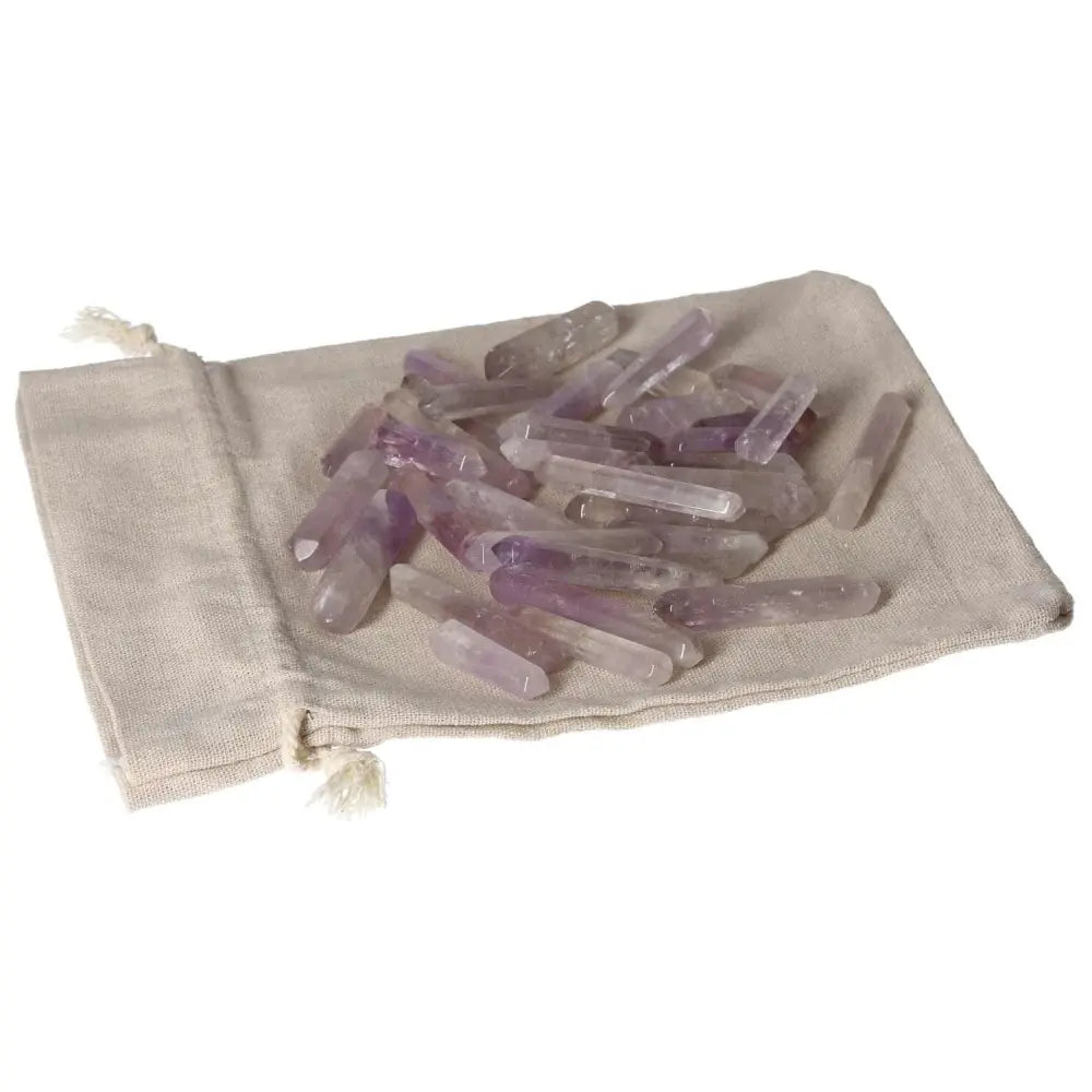 A collection of amethyst small sticks displayed on a beige cloth, valued for stress reduction, energy boost, and concentration enhancement.