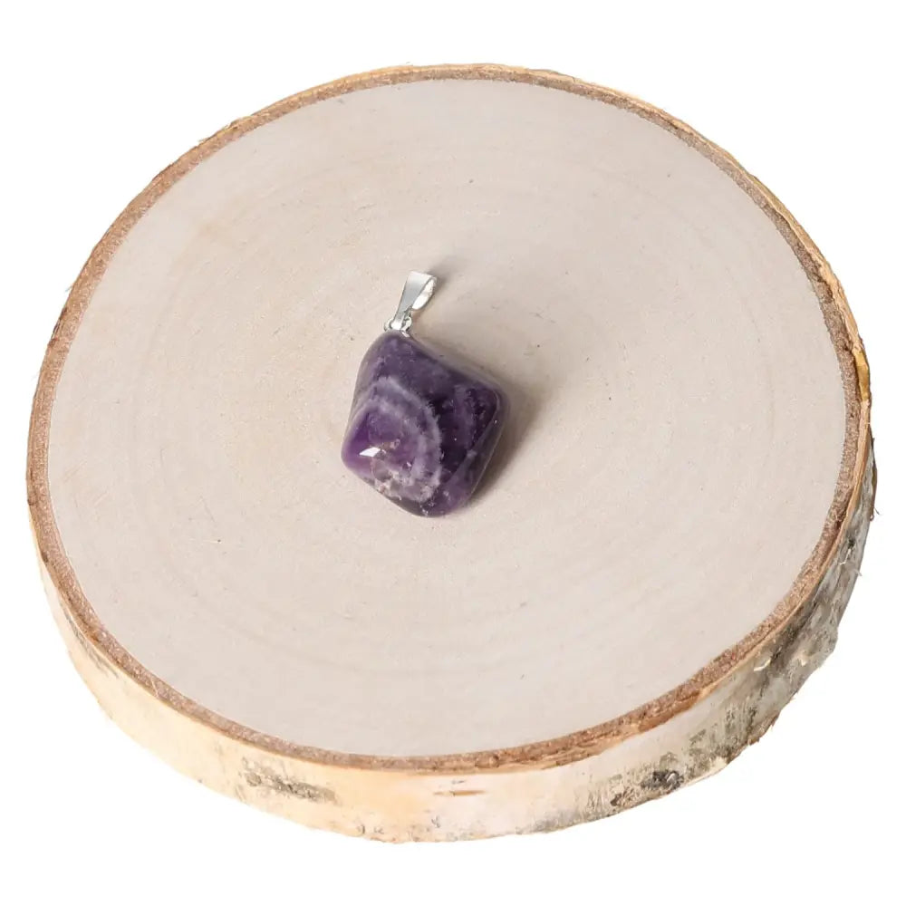 Amethyst Zebra Tumbled Pendant with purple hues and zebra patterns, displayed on a wooden surface, known for its calming energy.