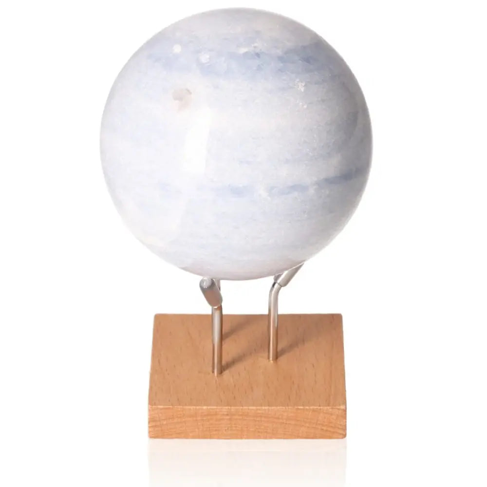 Blue Calcite Sphere on wooden stand, ideal for stress relief and emotional healing. Enhance communication and spiritual growth.