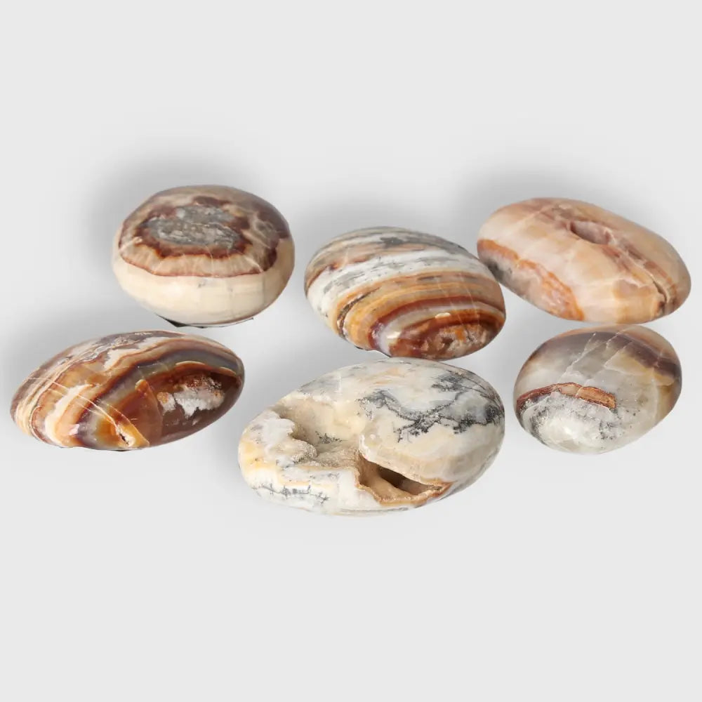 Collection of smooth brown aragonite palm stones with natural earthy tones, ideal for meditation and stress relief.