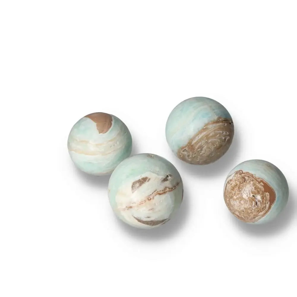 Four Caribbean Calcite spheres showcasing ocean blues and whites, symbolizing harmony and tranquility, by Sylvia Crystals.