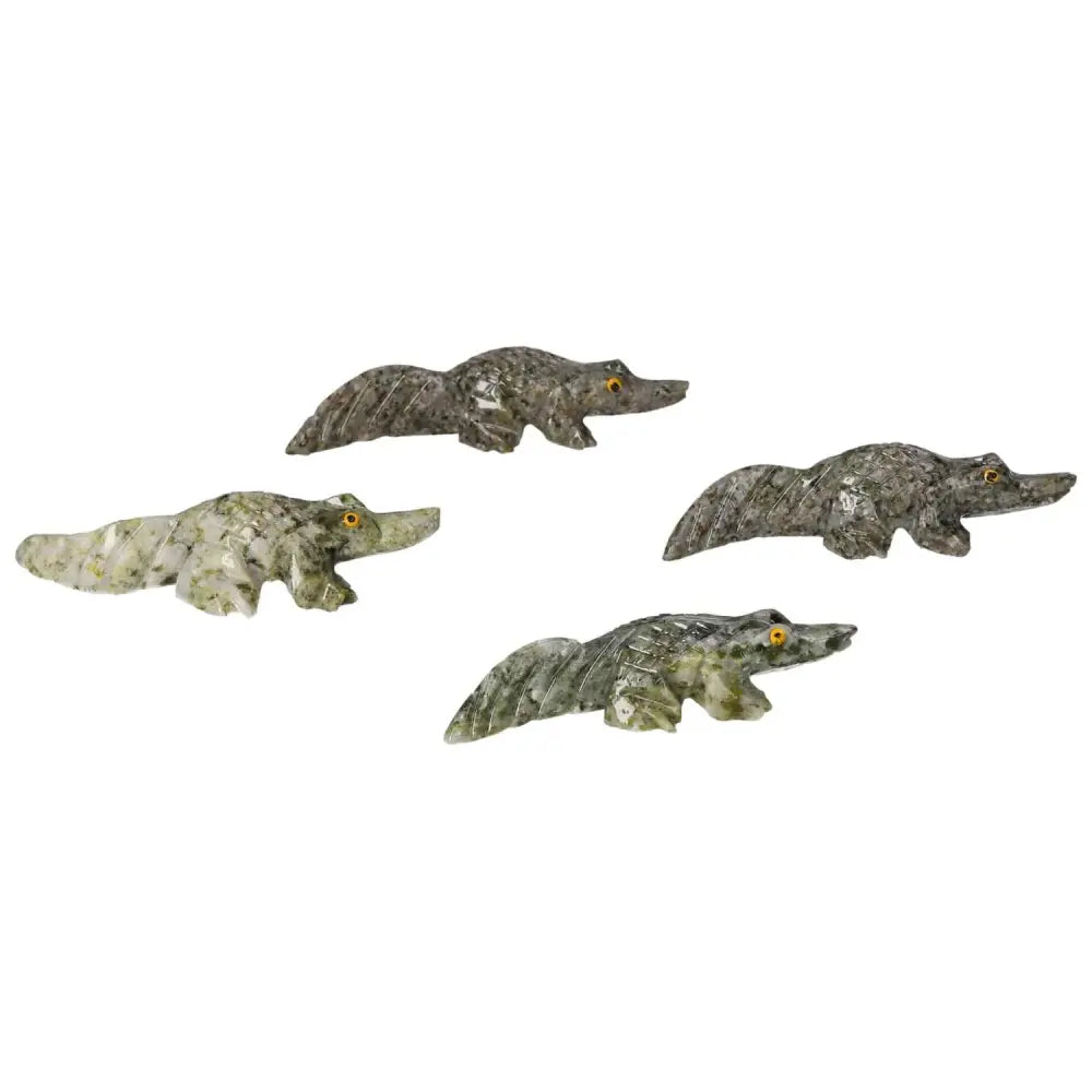 Four intricately carved dolomite alligators on a white background, showcasing fine craftsmanship and luxury from Sylvia Crystals.