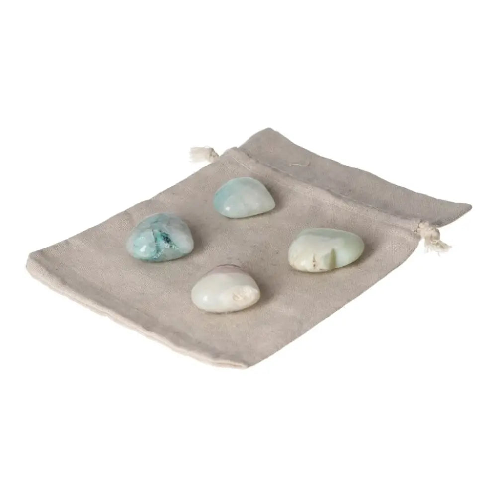 Four polished chrysocolla stones on a beige fabric pouch, symbolizing feminine energy and communication wisdom.