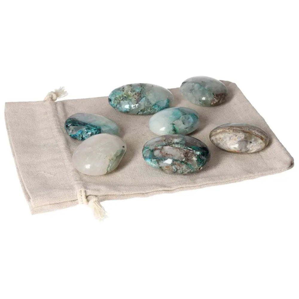 Chrysocolla palmstones displayed on a beige pouch, showcasing their natural green and blue hues, symbolizing communication and feminine energy.