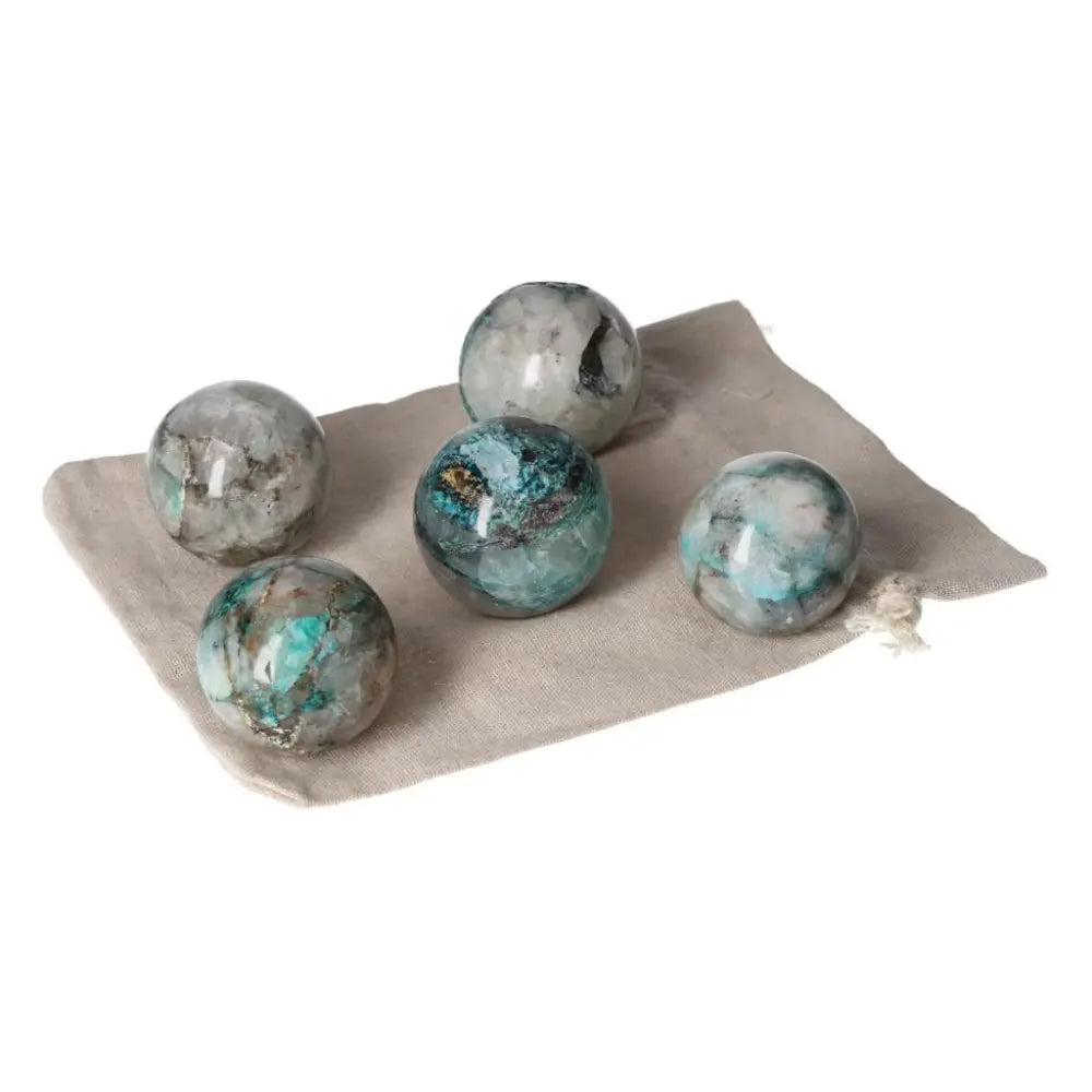 Five chrysocolla spheres with blue and green hues on a fabric bag, symbolizing communication and feminine energy benefits.