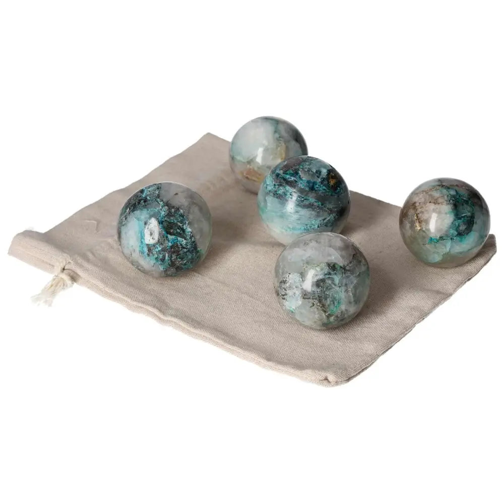 Collection of chrysocolla spheres on a beige cloth, showcasing their vibrant blue-green hues and powerful energy properties.