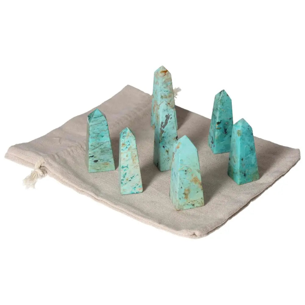 Collection of Chrysocolla towers on a beige cloth, showcasing vibrant green-blue hues and smooth finishes, known for enhancing communication skills.