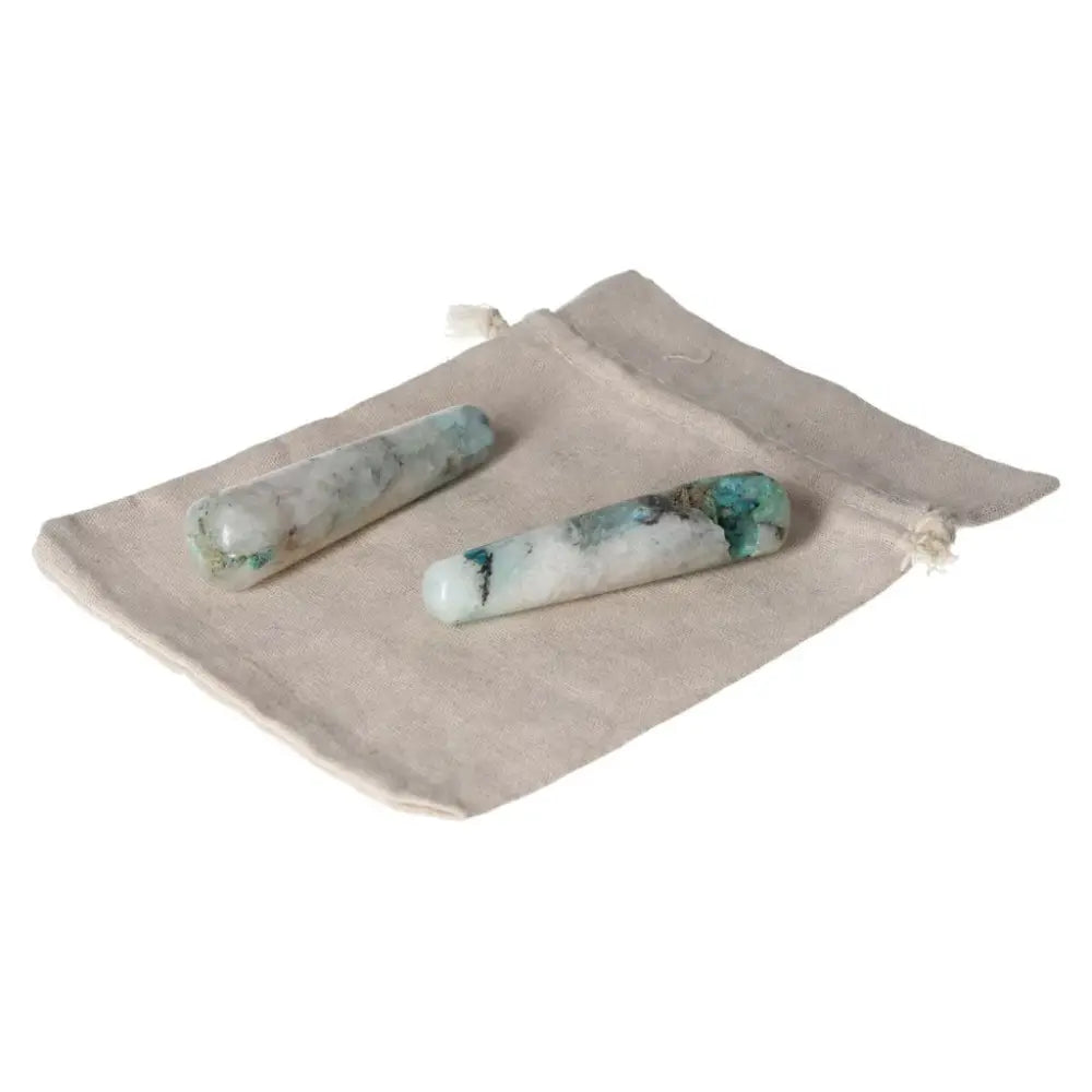 Two chrysocolla wands on a beige cloth, known for enhancing communication and promoting feminine energy.