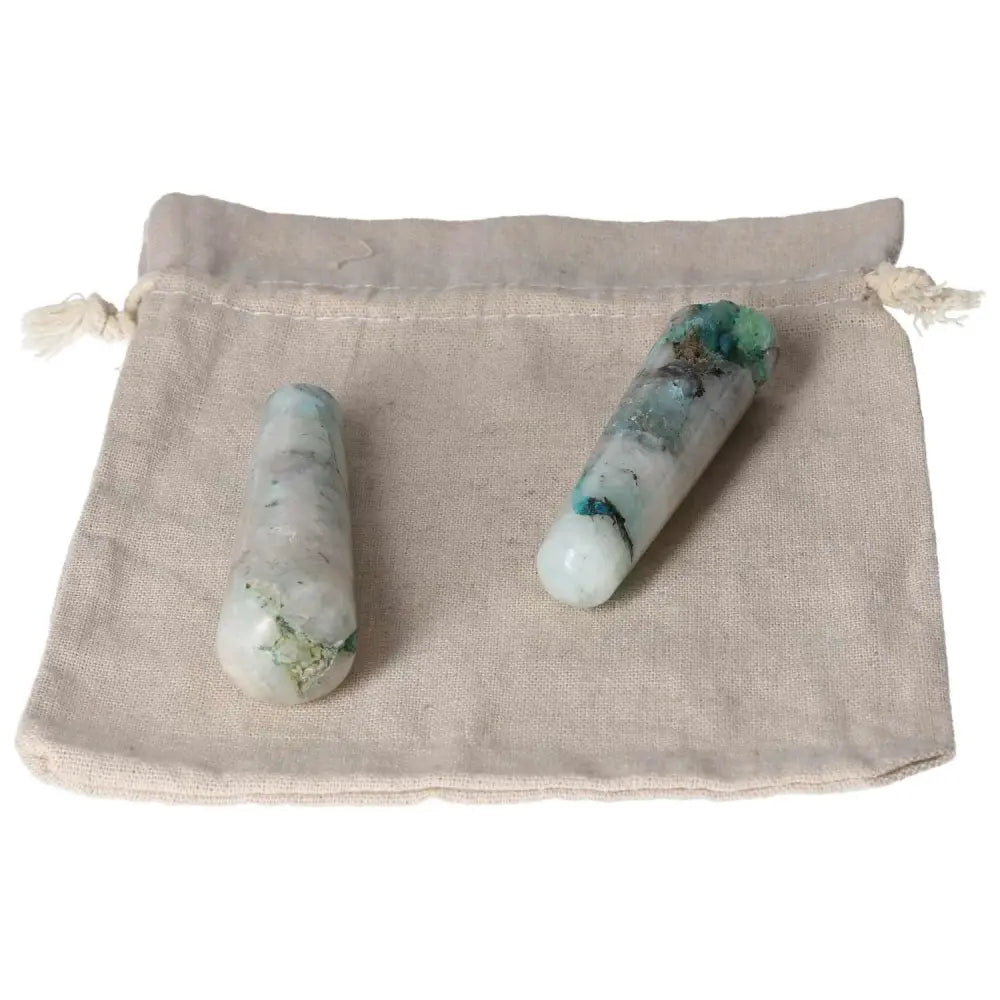 Two chrysocolla wands on a beige fabric pouch, known for enhancing communication and feminine energy.
