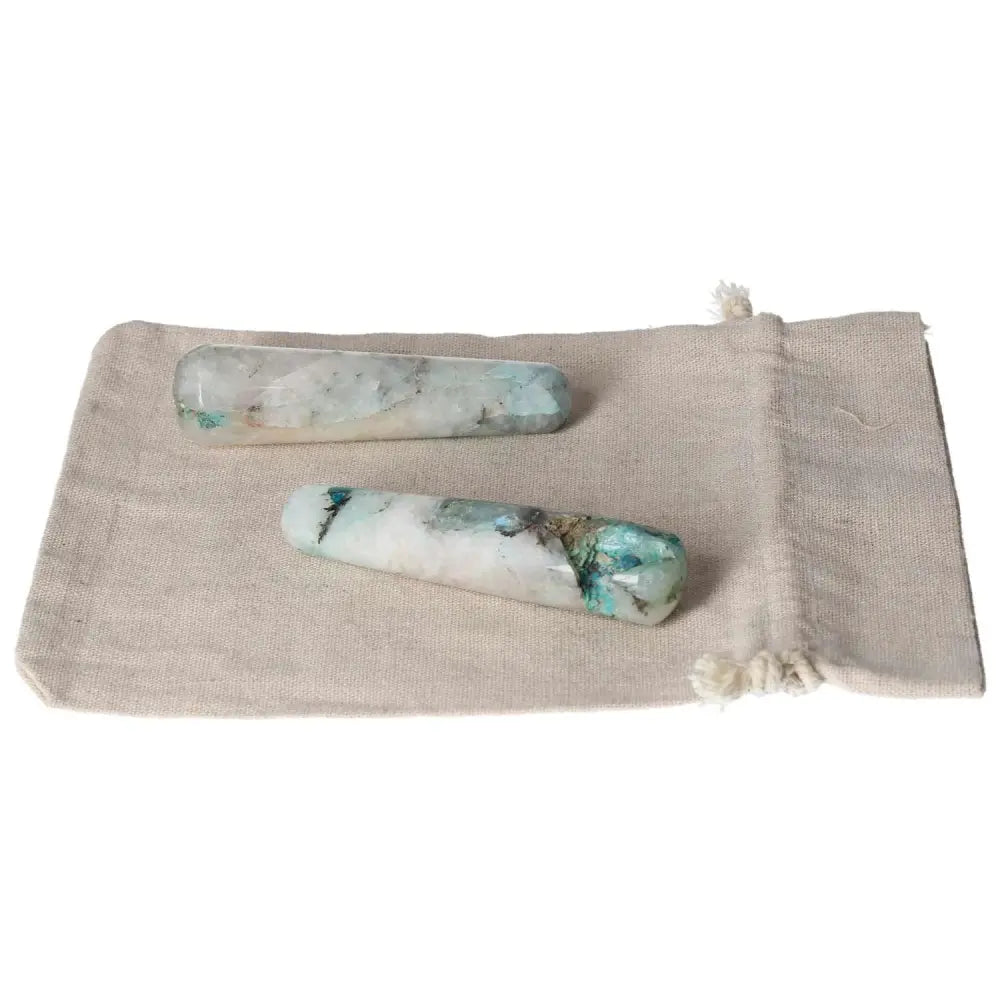 Two chrysocolla wands on a beige fabric bag, highlighting the stone's calming blue-green hues and natural healing properties.