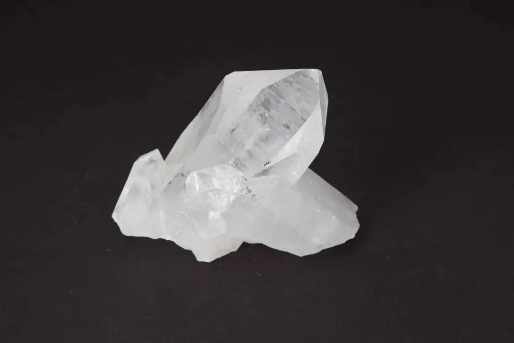Clear Quartz Cluster crystal with multiple points, amplifying energy and radiating clarity on a dark background. Ideal for harmony.