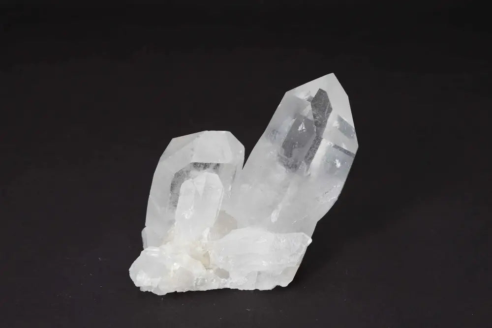 Clear Quartz Cluster on black background with multiple crystal points, amplifying energy and radiating clarity.