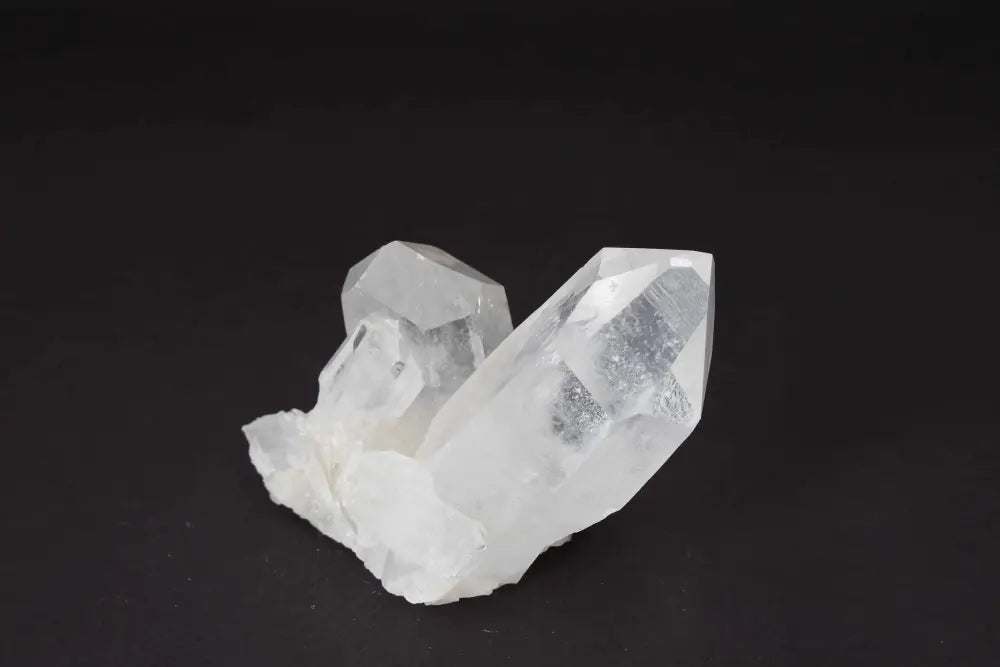 Clear Quartz Cluster with multiple crystal points on dark background, radiating clarity and high vibrational energy.