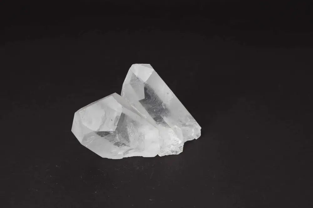 Clear Quartz Cluster with multiple crystal points, radiating clarity and high vibrational energy, on a dark background.