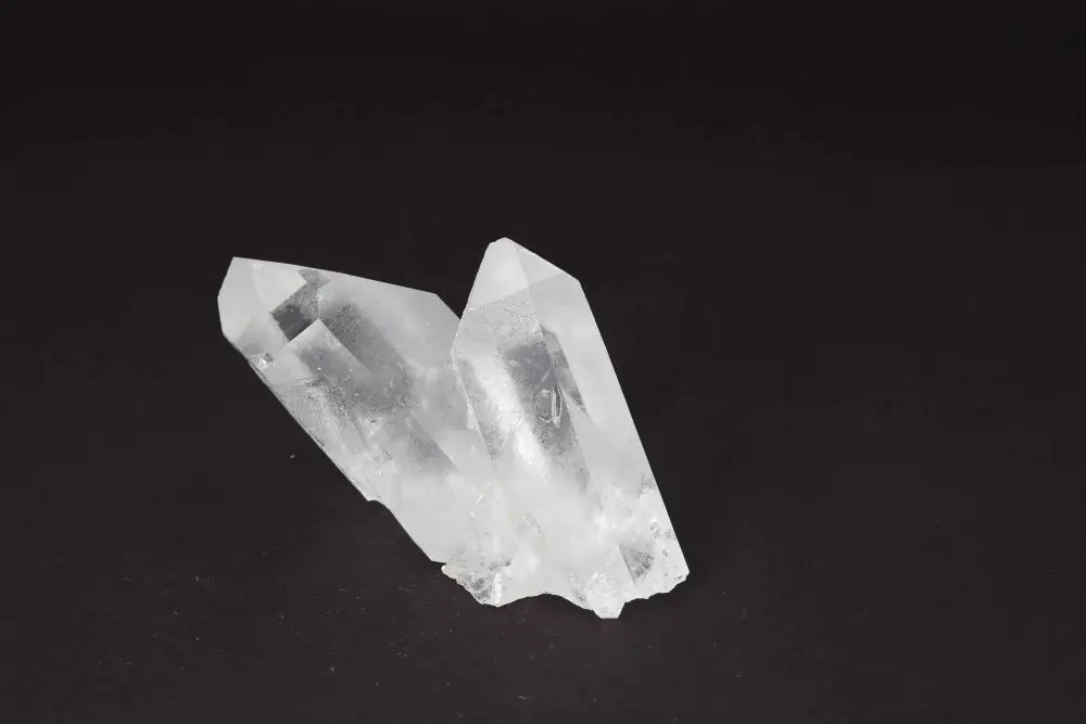 Clear Quartz Cluster on black background, showcasing multiple crystal points for energy amplification and purification.