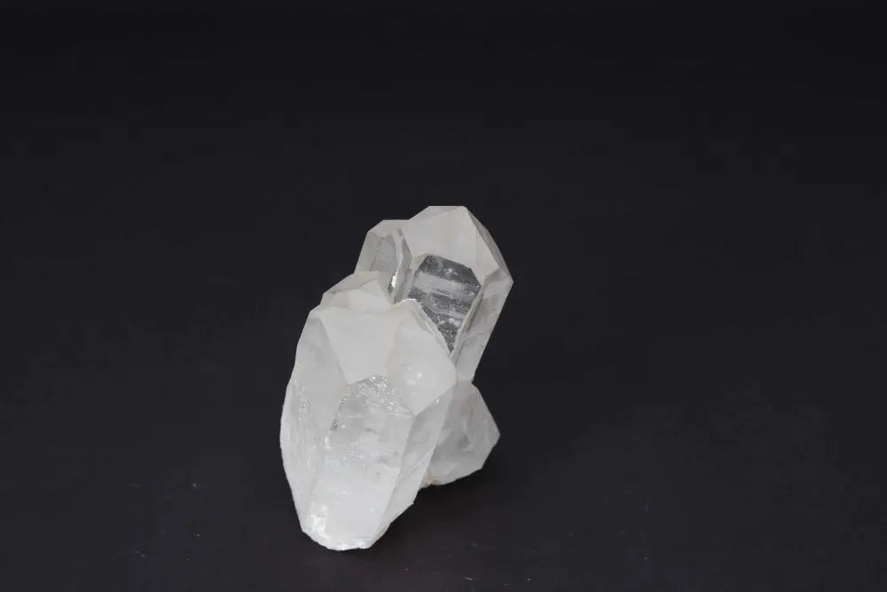 Clear Quartz Cluster on dark background, amplifying energy and clarity with multiple natural crystal points.