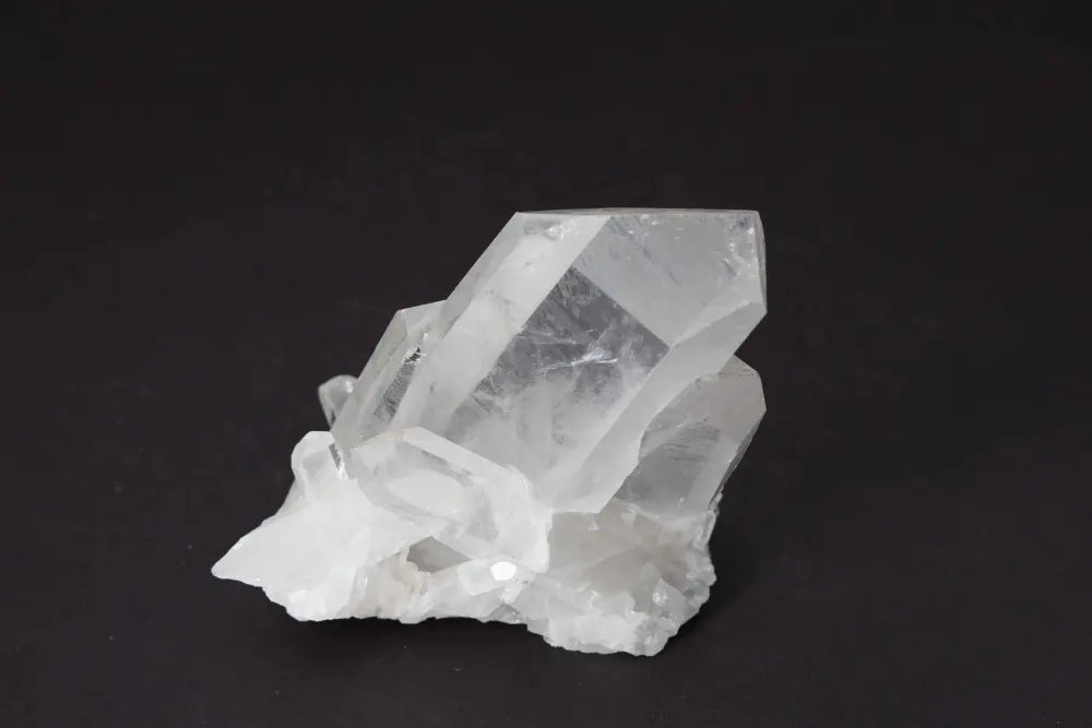 Clear Quartz Cluster with multiple crystal points on a dark background, radiating light and high vibrational energy.