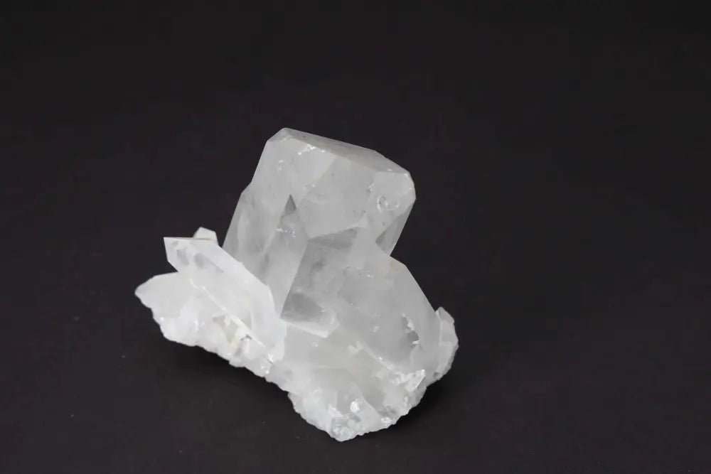 Clear Quartz Cluster showcasing natural crystal formation on dark background, known for amplifying and purifying energy in any space.