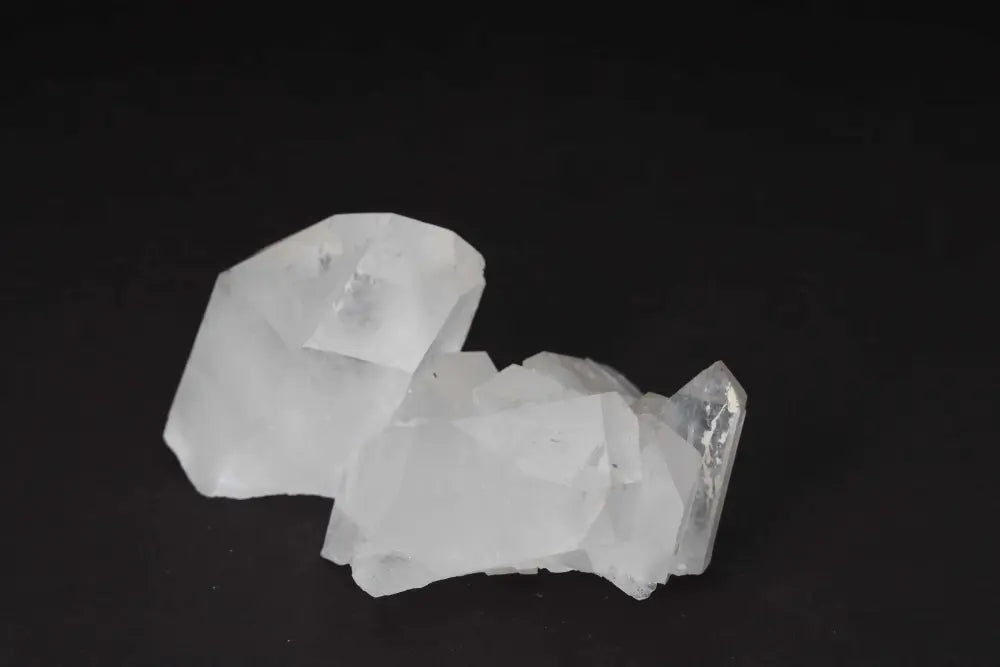 Clear quartz cluster with multiple crystal points radiating energy on a dark background.