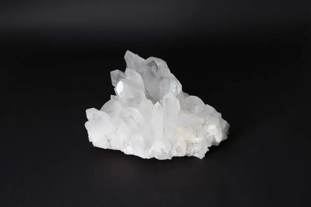 Clear Quartz Cluster on black background, showcasing natural crystal points and radiant clarity. Ideal for energy amplification.