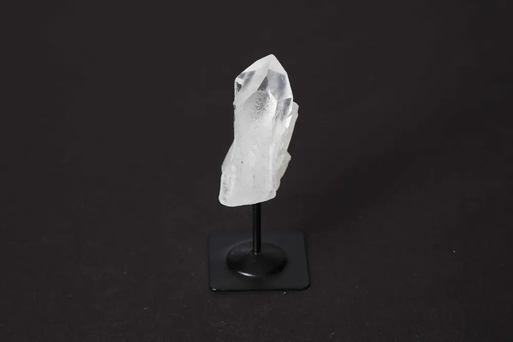 Clear Quartz on metal stand showcasing its crystalline beauty and spiritual healing properties against a dark background.