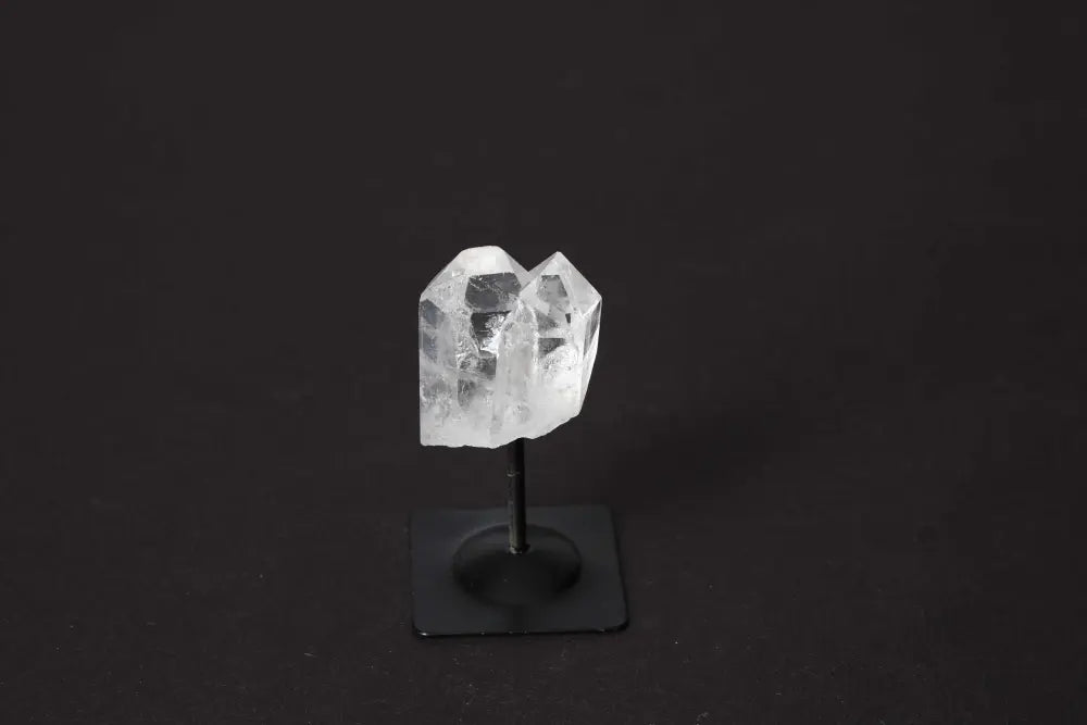 Clear quartz crystal on a metal stand, showcasing unique properties and energy, enhances chakra and zodiac connections.
