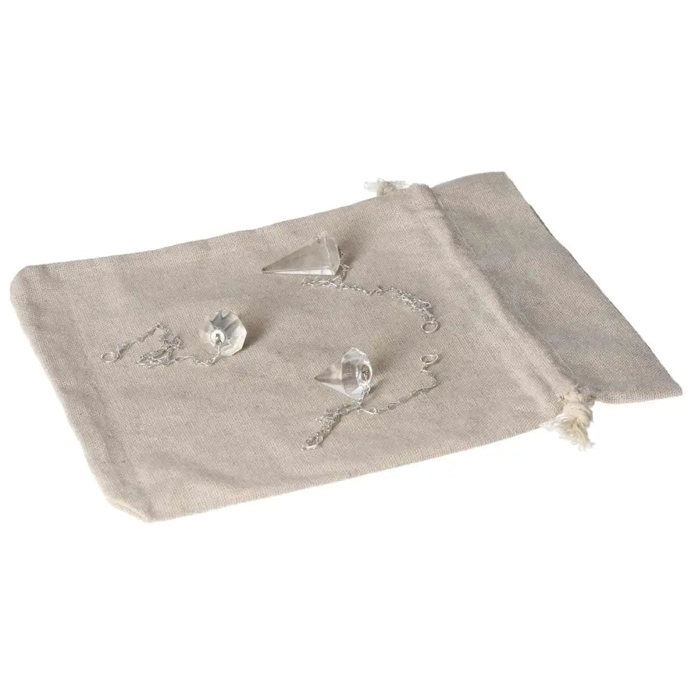 Clear Quartz Pendulum with chain on a linen cloth, ideal for energy purification and harmony.