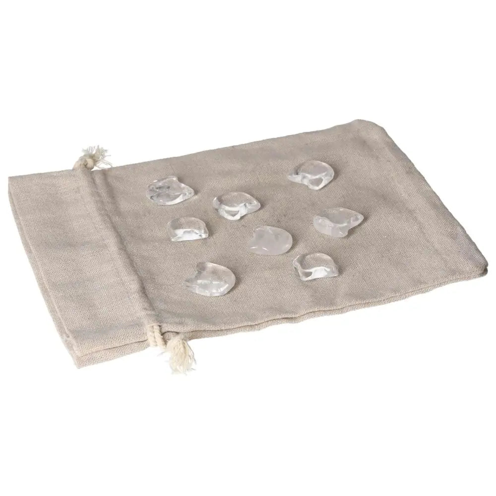 Collection of small clear quartz cat figures on a beige fabric bag, symbolizing clarity and playful energy, ideal for cat lovers.