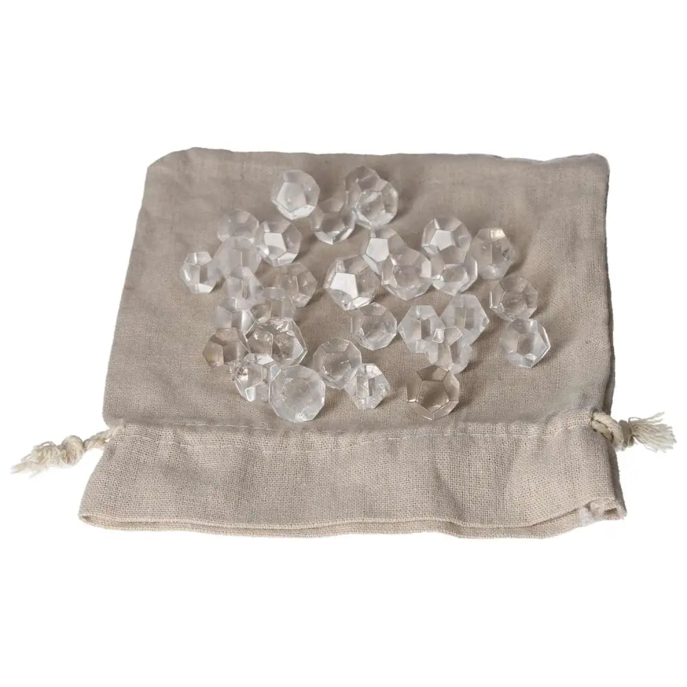 Clear Quartz small geometric spheres on a linen pouch, ideal for purification, harmonizing energy, and neutralizing negative vibrations.