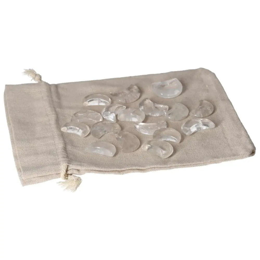 Small clear quartz moon-shaped stones on a fabric pouch, known for purifying energy and neutralizing negative vibrations.