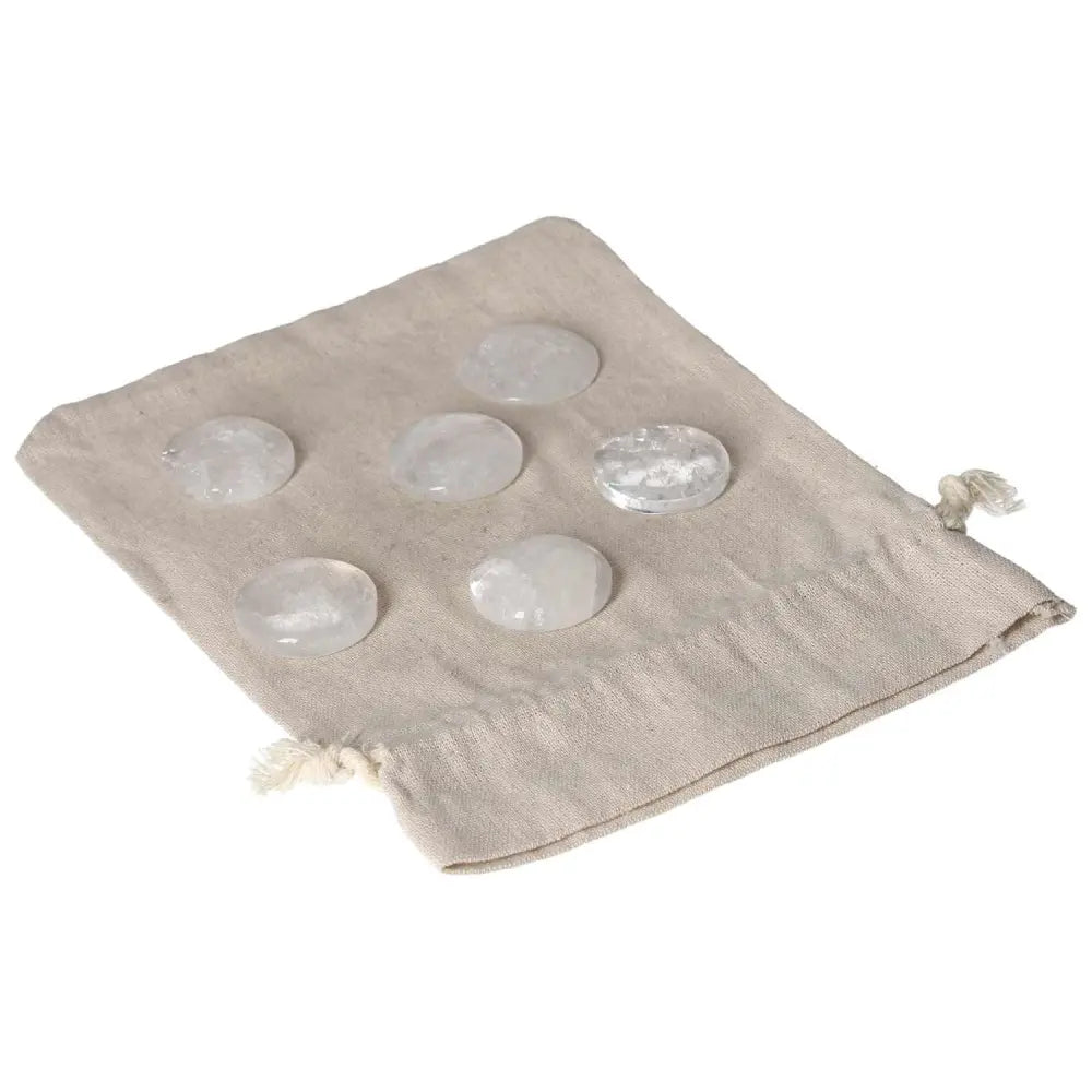 Clear quartz small palmstones on a beige fabric pouch, ideal for meditation and energy purification.