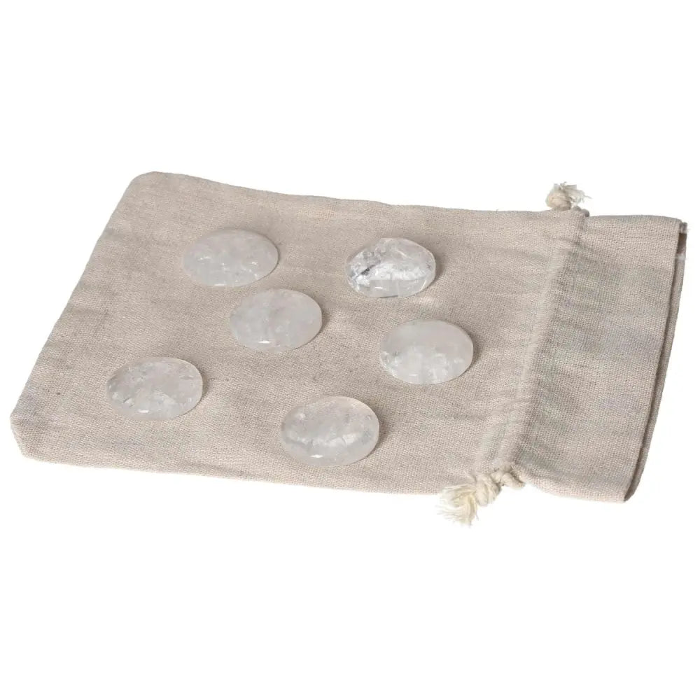 Clear Quartz small palmstone set on beige cloth bag for purification and energy harmonization.