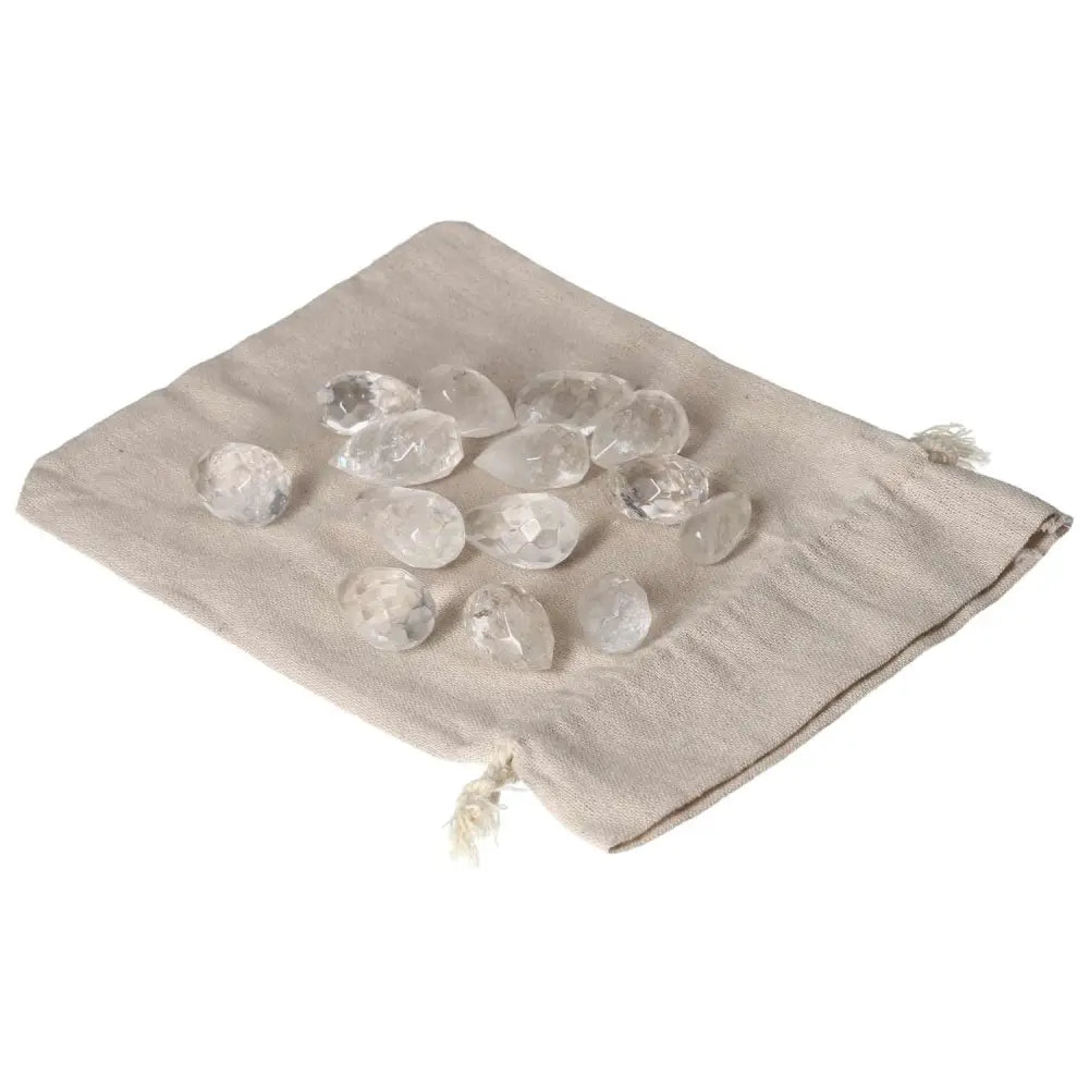 Clear Quartz small tear-shaped stones on a beige cloth bag, known for purification and energy harmonizing properties.