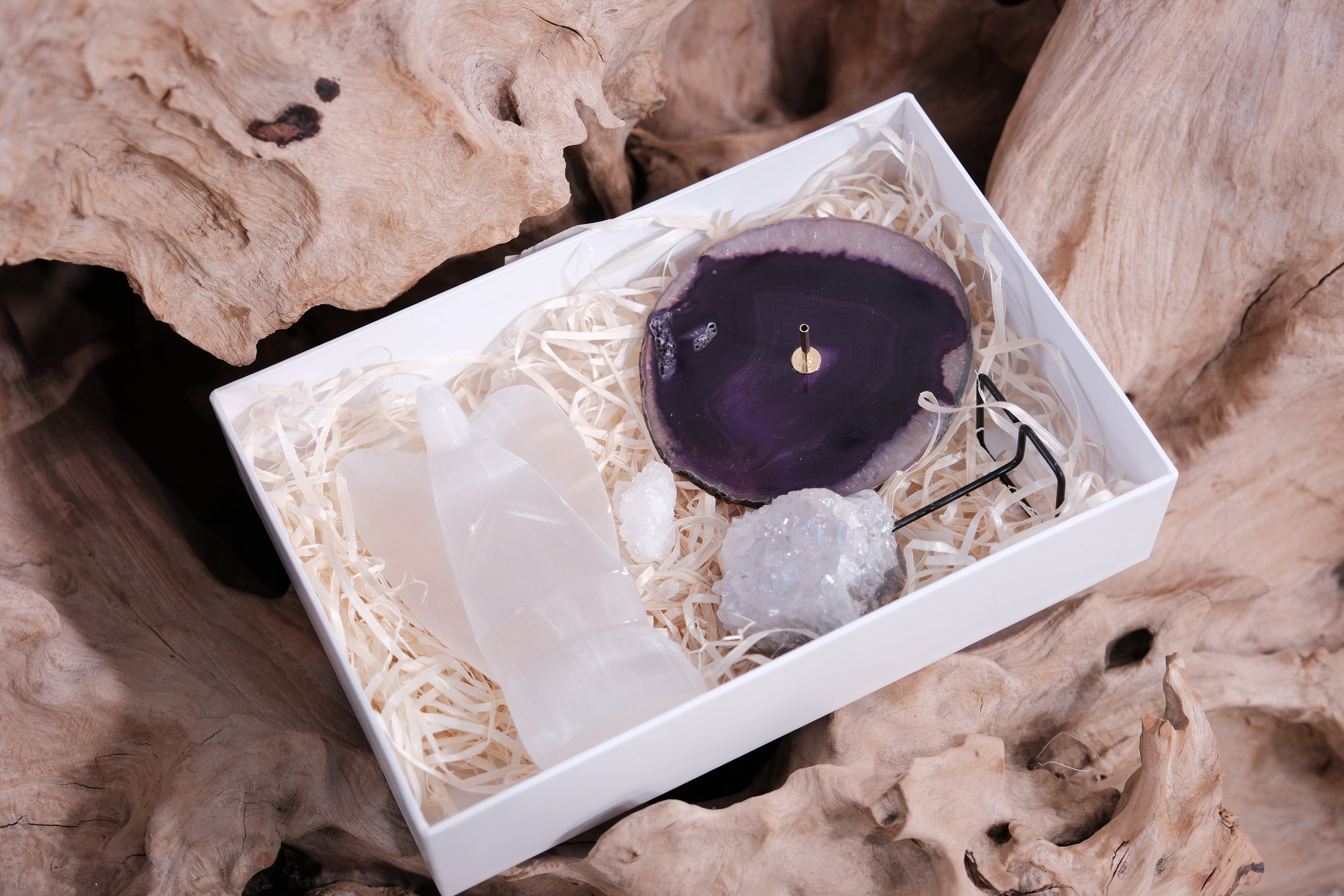 Christmas gift box with hand-selected crystals for peace, beauty, and positive energy in a white box on wood background.