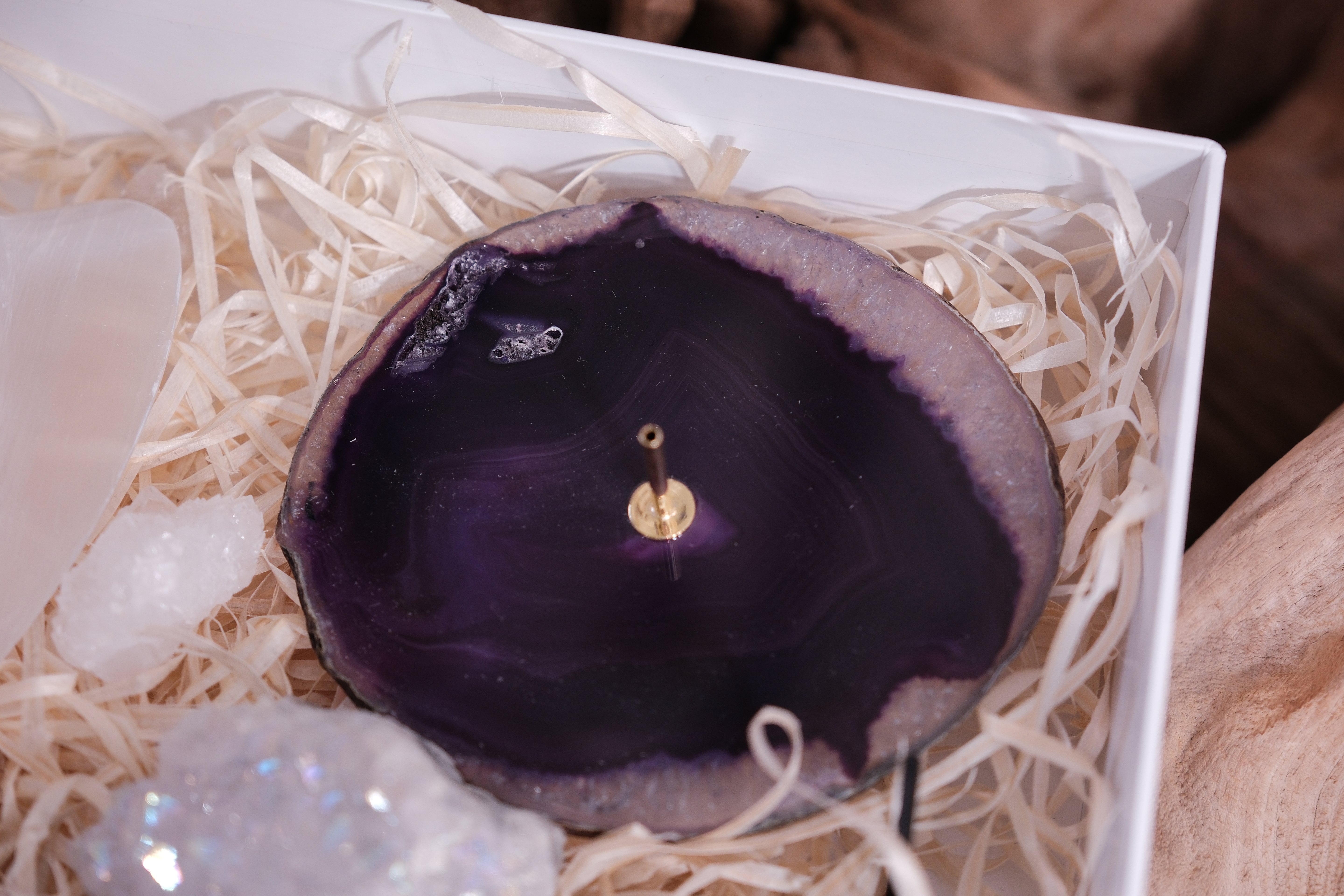 Purple agate crystal in Sylvia Crystals Christmas Gift Box, surrounded by decorative straw and shimmering stones.