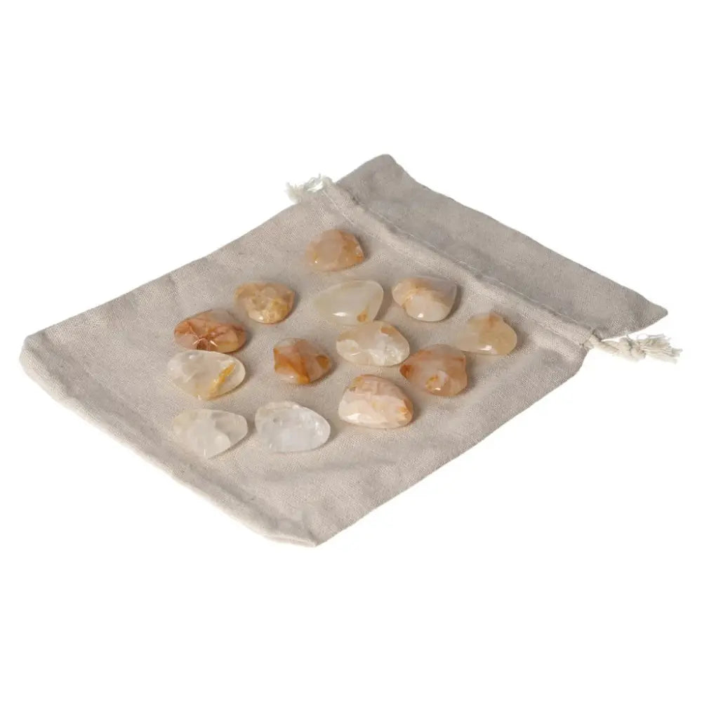 A collection of Golden Healer small heart-shaped stones displayed on a beige pouch, showcasing their unique patterns and warm hues.