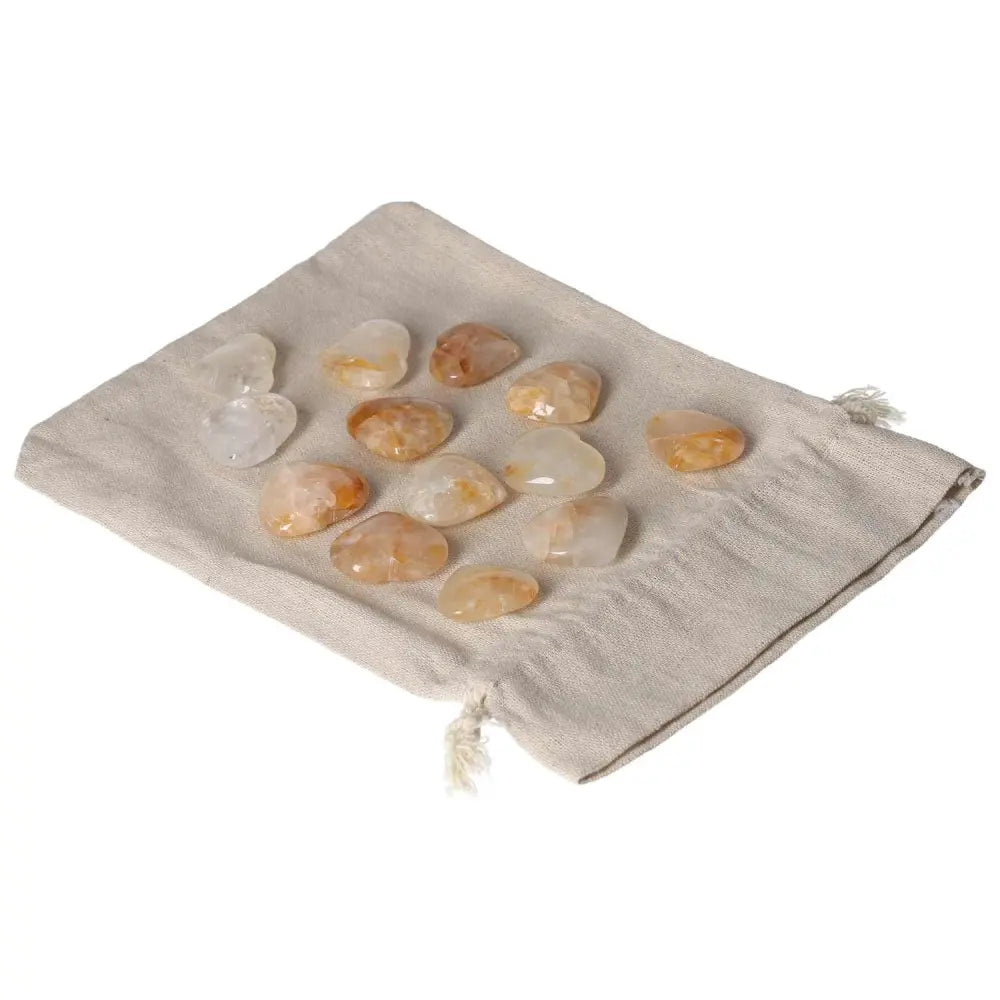 Golden Healer small heart stones on a cloth pouch, showcasing their radiant hues and healing properties.