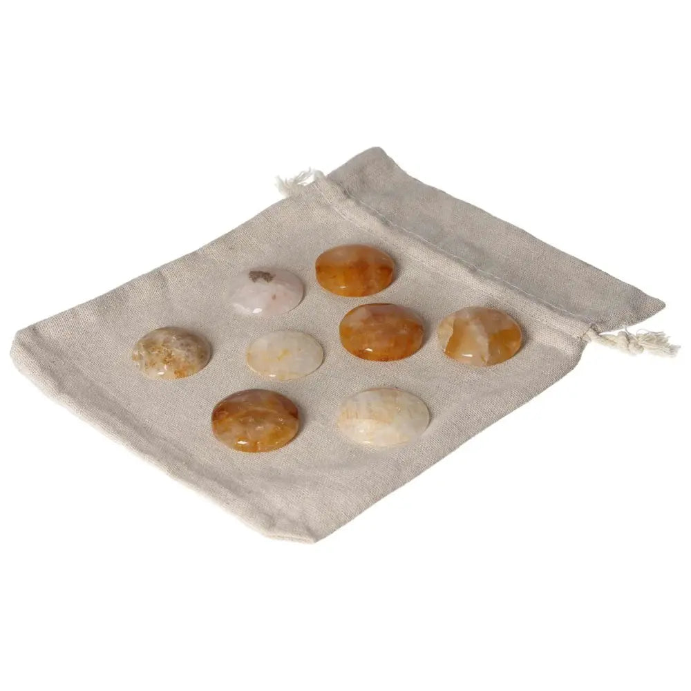 Golden Healer small palmstones displayed on a beige drawstring pouch.