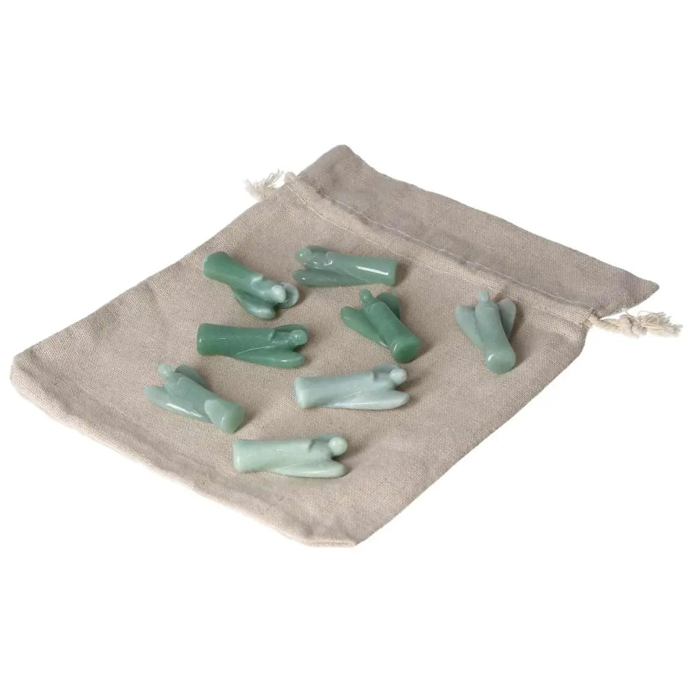 Collection of small green aventurine angel figurines on a beige cloth bag, symbolizing luck and positivity, enhances self-confidence.