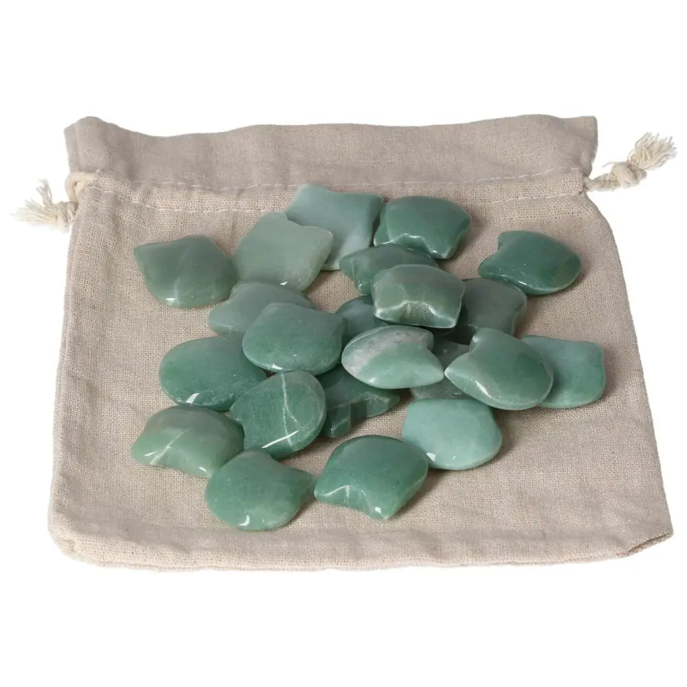 Collection of green aventurine stones on a beige drawstring bag, showcasing their smooth, polished surfaces and calming green hues.