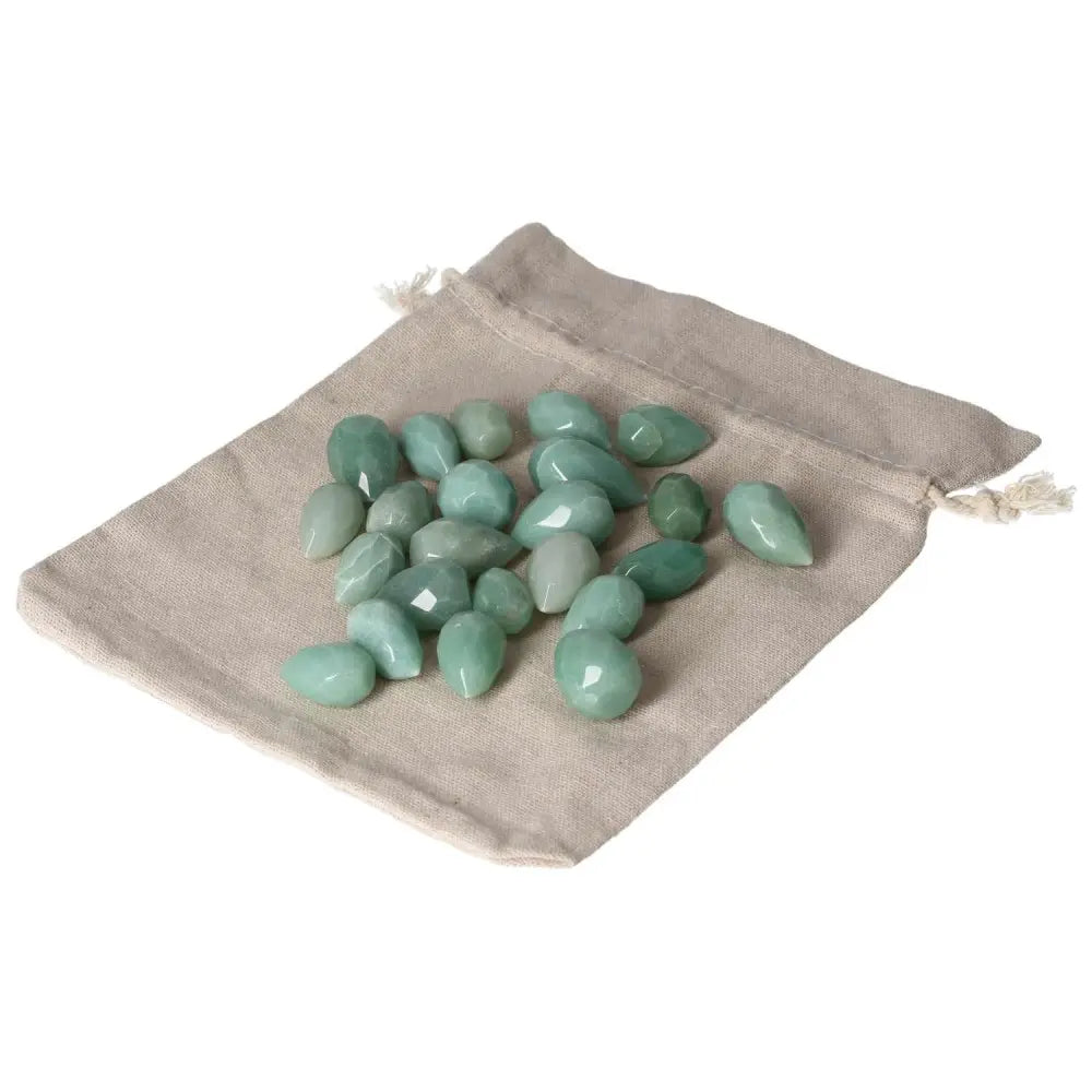 Small tear-shaped green aventurine stones on a beige cloth bag, symbolizing luck, harmony, and new ventures.