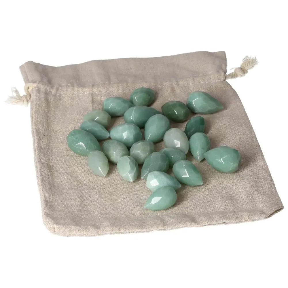Green Aventurine Tear-shaped Stones on Beige Fabric, Promoting Self-confidence and Prosperity with Calming Energies.