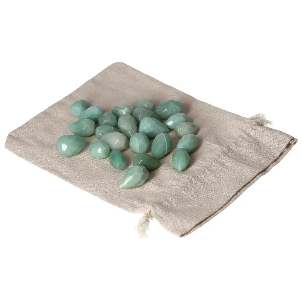 Smooth green aventurine tear stones on a beige cloth, symbolizing luck and prosperity.